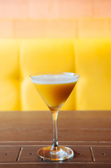 Sweet mango juice smoothie in cocktail glass with bright yellow colour background