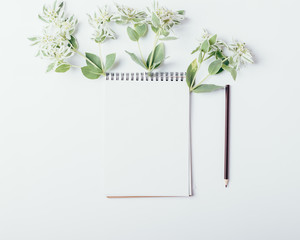 Mock-up with clean notepad and small green flowers