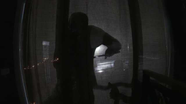 Bandit picking lock. Two shadows of thieves coming into flat. Balcony. Drapes. Indoors. Without faces. Night. Darkness.
