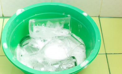 Close up view and copy space. Glass of water soaked in green plastic basin with foam.