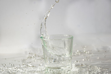 Glasses of water falling and jumping with splashes and drops