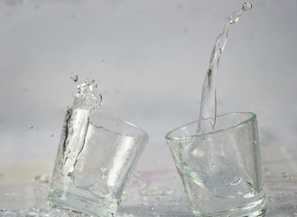 Glasses of water falling and jumping with splashes and drops