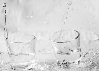 Glasses of water falling and jumping with splashes and drops