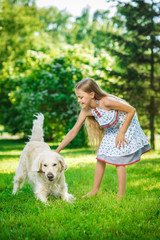 Little girl with golden retriever dog in the park