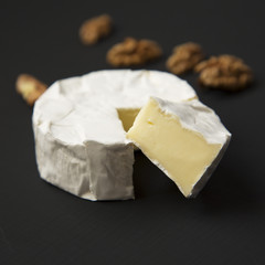 Fototapeta na wymiar Cheese camembert or brie with walnuts on dark background. Milk production. Side view. Closeup.