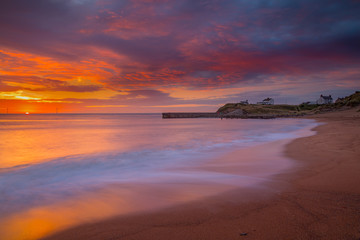 Obraz premium Sunrise over Seaton Sluice Beach and Harbour entrance on the coast of Northumberland, England, UK.