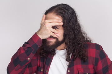 Portrait of handsome funny man with beard and black long curly hair in casual style, checkered red...