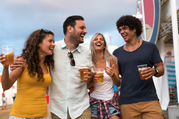 Enjoying beer with friends. Young people hanging out and enjoying drinks at music festival.