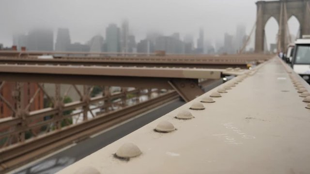 A sliding establishing shot of the support structure on the Brooklyn Bridge on an overcast day.  	