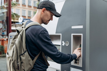 Tourist buys tickets for land or underground transport in Germany. Independent purchase of tickets for the tram, bus and train in a modern street machine.