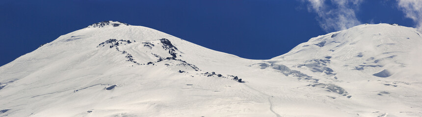 Climbers trail on Mount Elbrus. The eastern peak is covered with snow. North Caucasus, Russia.