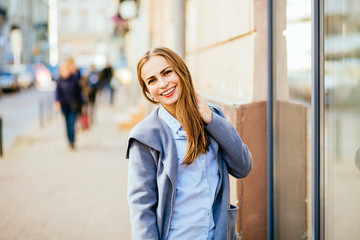 Brunette trendy woman portrait of young pretty trendy girl posing at the city in Europe, autumn street, laughing and smiling portrait.