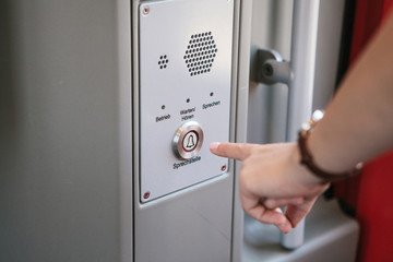 The person presses the button to call and talk with the support service of the train or subway. The...