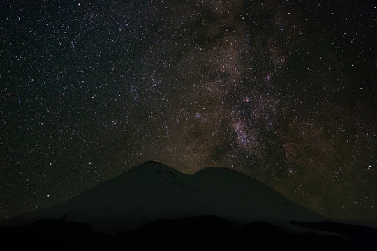 Stars of the Milky Way at night in the sky above Mount Elbrus. View of the northern slope of the two peaks of the stratovolcano. The highest peak of Russia and Europe is 5642m. 