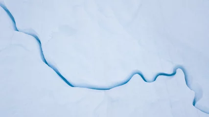 Selbstklebende Fototapeten Gletscher Aerial view from a drone flying over a frozen glacier with a small melt water lake on top. Disko bay, Greenland.  © Kertu