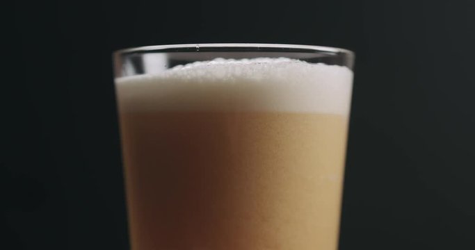 Closeup slow motion light ale beer with bubbles over black background
