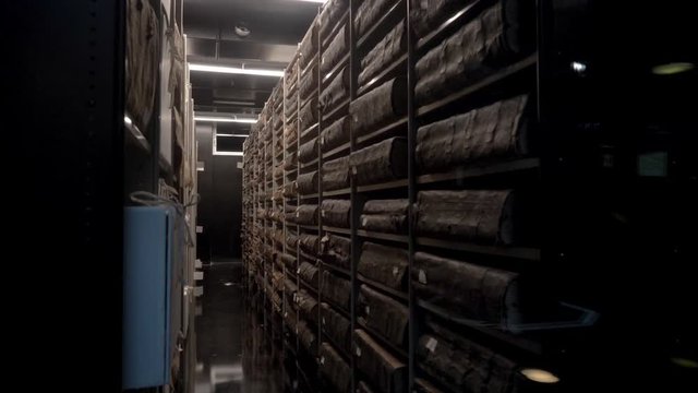 A slow pan revealing big books in an old archive, gaurded behind glass. At de Bazel in Amsterdam, the Stadsarchief.