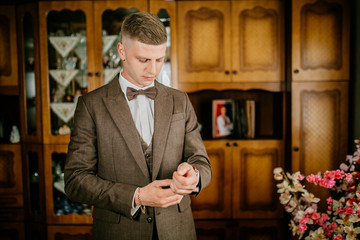 stylish groomsmen helping happy groom getting ready in the morning for wedding ceremony. luxury man...