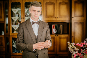 stylish groomsmen helping happy groom getting ready in the morning for wedding ceremony. luxury man...