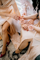 Bridesmaids helping slender bride lacing her wedding white dress, buttoning on delicate lace pattern with fluffy skirt on waist. Morning bridal preparation details newlyweds. Wedding day moments.