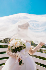 Pretty happy bride in luxury dress with bouquet of roses. Wedding photoshoot outdoor. Beautiful...
