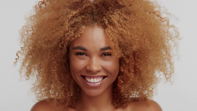 mixed race woman with big curly afro blonde hair laughing making surprised face