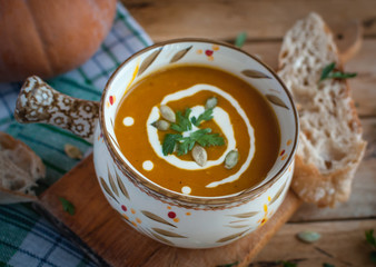 Roasted pumpkin soup in bowl on wooden background