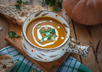 Roasted pumpkin soup in bowl on wooden background
