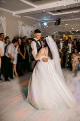 the bride and her husband dance together their first wedding dance in the restaurant. Fog around newlyweds.