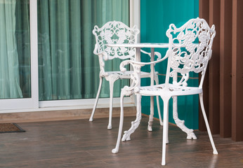 White bench set on wooden floor in front of house.