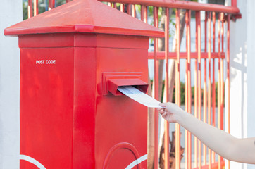 Hand dropping mail into red mailbox sending  wish to other people