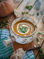 Roasted pumpkin soup in bowl on wooden background