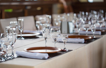 Glasses, forks, knives, plates on a table in restaurant served for dinner