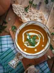 Roasted pumpkin soup in bowl on wooden background, top view