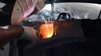 Welding steel with electricity in auto body repair shop, closeup, 4k