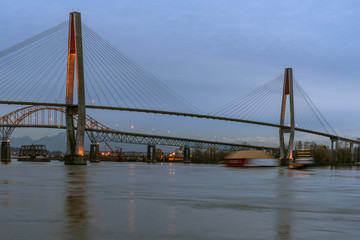 Bridge Over Fraser River with Motion Blurred Tug Pulling Barge in New Westminster British Columbia