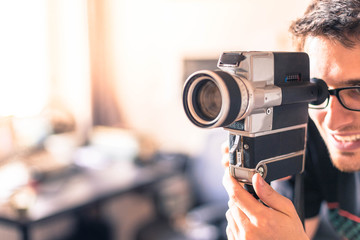 Junger Mann dreht mit Vintage/Retro-Kamera einen Film für ein Filmfestival 