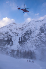 rescue team with a red helicopter rescuing a hurt skier
