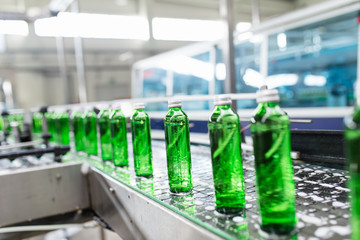 Bottling plant - Water bottling line for processing and bottling pure spring water into green glass bottles. Selective focus.