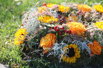 Blumen im Trauerkranz nach Beerdigung mit Rosen in Gelb und Sonnenblumen 