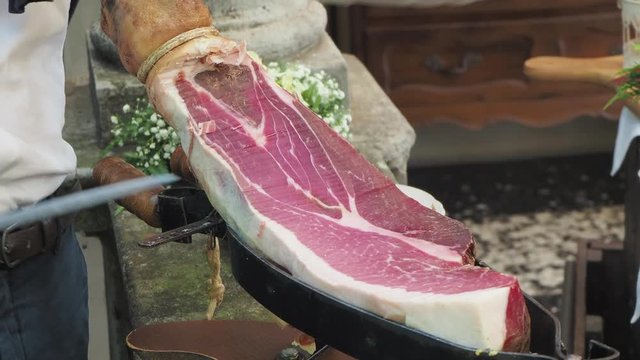 Waiter slices a leg of high quality raw ham