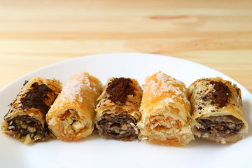 Row of delectable Baklava sweets on a white plate served on wooden table 