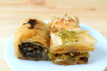 Close up of Baklava Pastries in Different Flavors on White Plate Served on Wooden Table 