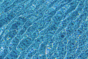 Ripple and clear water in swimming pool with reflection from sunrise blue sky background.