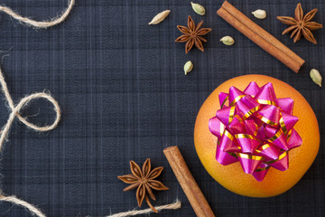 Decorative christmas rope with one orange citrus on a dark blue background