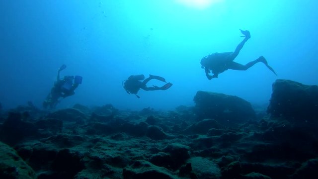 Silhouette view of scuba divers swimming over reef in Kas, Turkey