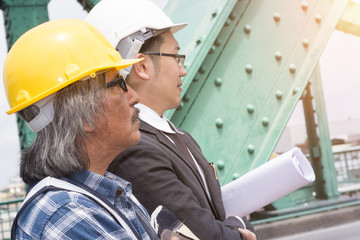 Handsome business engineer of maneger man stressing and taking about success work with partners.Male and partnership in black suite , plaid shirt and helmet.