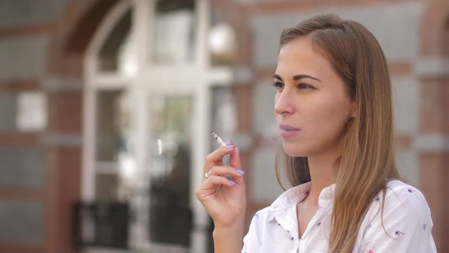 Young beautiful woman smokes on the street. 4k. slow motion