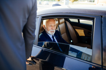 Senior business man sitting in his limousine. Business concept. Back light. - obrazy, fototapety, plakaty
