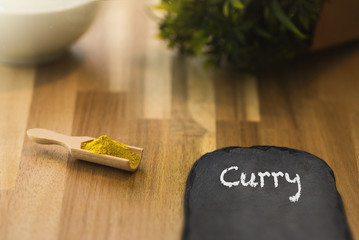 Curry spice powder on a wooden spoon and a slate